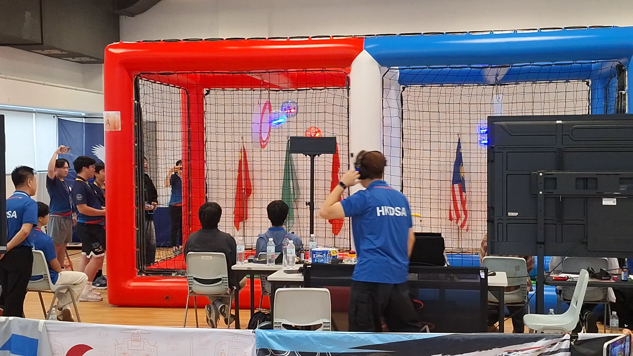 Scoring officials viewing a drone-sports goal through the arena net